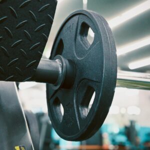Detailed view of a barbell weight plate in a sleek, modern gym environment.